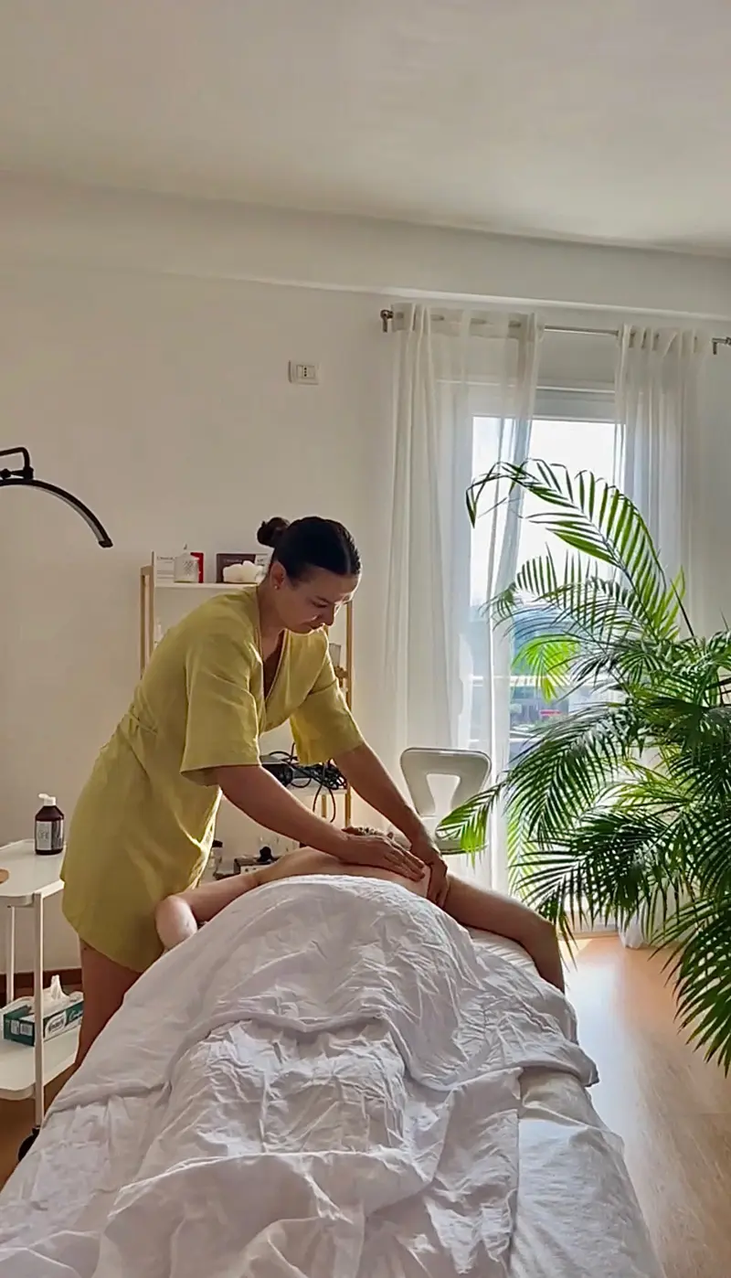 Therapist giving a back massage in the bright Sundara Studio treatment room